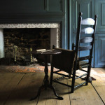 A high-backed wooden chair, side table, bone pipe, and formal hearth in the museum's 18th-century "formal parlor"