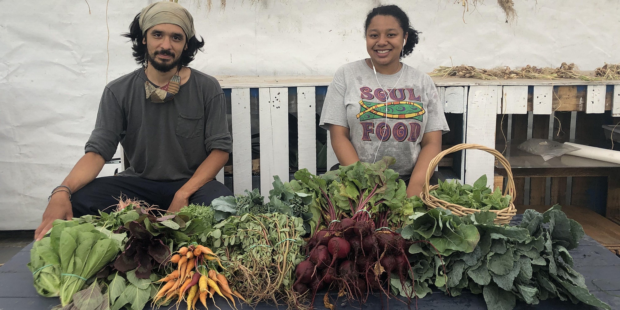 Farmers Zach & Anissa in front of a harvest of vegetables from the Wyckoff Farm.